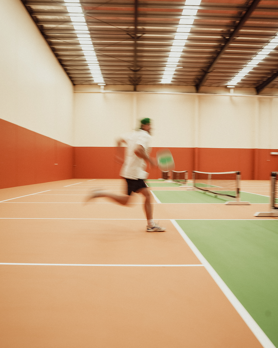 Pickleball player moving across an indoor court